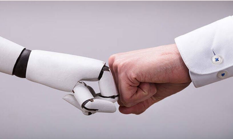 A robot hand and a human hand doing a fist bump